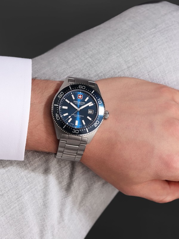 SWISS MILITARY HANOWA NOMAD SMWGH0004904 – Swiss Made muški sportski sat prepoznatljivog vintage dizajna iz 1970-ih. Kućište od nerđajućeg čelika i plavi brojčanik sa odgovarajućim prstenom u plavoj boji stvaraju skladan i moderan izgled. Sat poseduje safirno staklo, kvarcni mehanizam Ronda 515 sa funkcijom datuma i vodootpornost do 100 metara – idealan spoj švajcarske preciznosti i muževne elegancije.