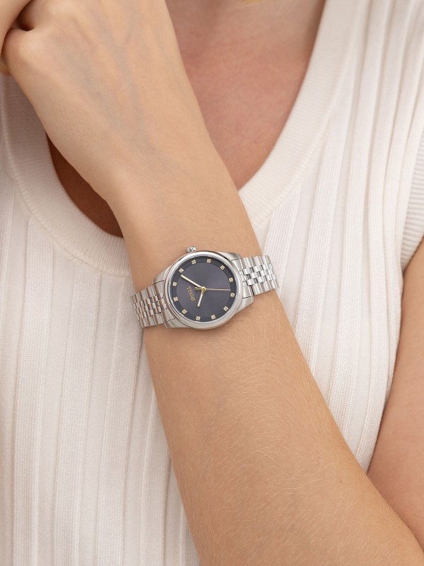 BOSS GRACEFUL PRECIOUS 1502809 – elegantan ženski sat izrađen od nerđajućeg čelika u boji srebra, sa teget brojčanikom ukrašenim cirkonima koji dodaju sofisticirani sjaj. Okruglo kućište prečnika 32mm, mineralno staklo, kvarcni mehanizam i vodootpornost do 30m čine ovaj sat savršenim spojem luksuza i prefinjenog stila za svaku priliku.