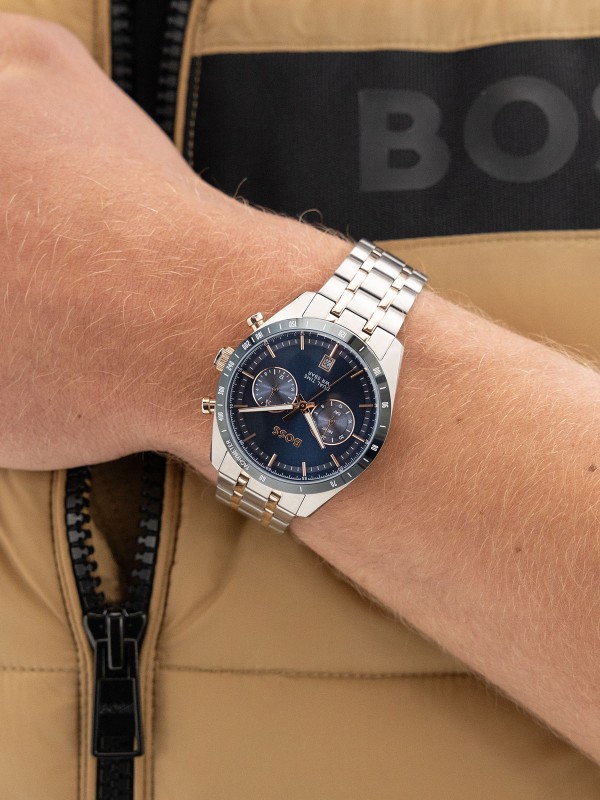 BOSS TOURMASTER 1514288 – muški dual time sat sa plavim “panda” brojčanikom i tahimetrom. Kućište od nerđajućeg čelika u boji srebra sa plavom koronom i narukvica u kombinaciji srebra i roze zlata. Elegantni retro dizajn sa savremenim detaljima.