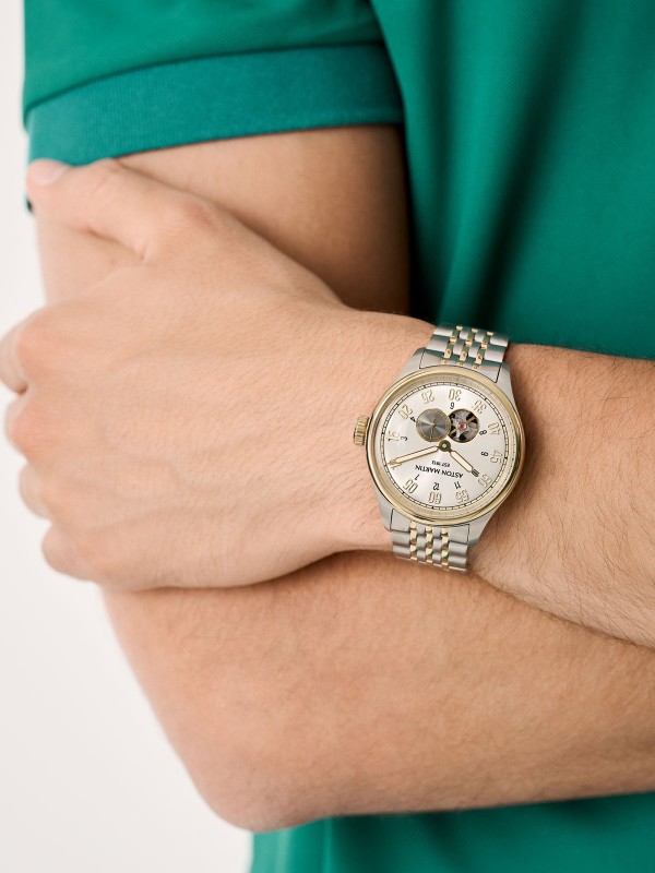Aston Martin MTTS1F503 – elegantni automatik sat koji odražava spoj britanskog luksuza i vrhunske izrade. Kućište od nerđajućeg čelika prečnika 41mm sa skeleton srebrnim brojčanikom i istorijskim Aston Martin logom iz 1913. godine pruža bezvremenski izgled. Transparentna poleđina otkriva automatski mehanizam sa rotorom u podium zelenoj boji, dok narukvica u kombinaciji srebrne i žutog zlata donosi sofisticiran kontrast. Savršen izbor za muškarce sa stilom i stavom.