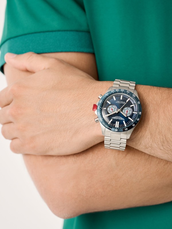 Aston Martin MTIS1F503 – muški hronograf sa teget brojčanikom i svetloplavim podbrojčanicima. Kućište od recikliranog nerđajućeg čelika sa plavom koronom i tahimetarskom skalom. Osvetljene kazaljke, crveni akcenti i vodootpornost do 100m spajaju sportski duh i luksuznu estetiku Aston Martin brenda.