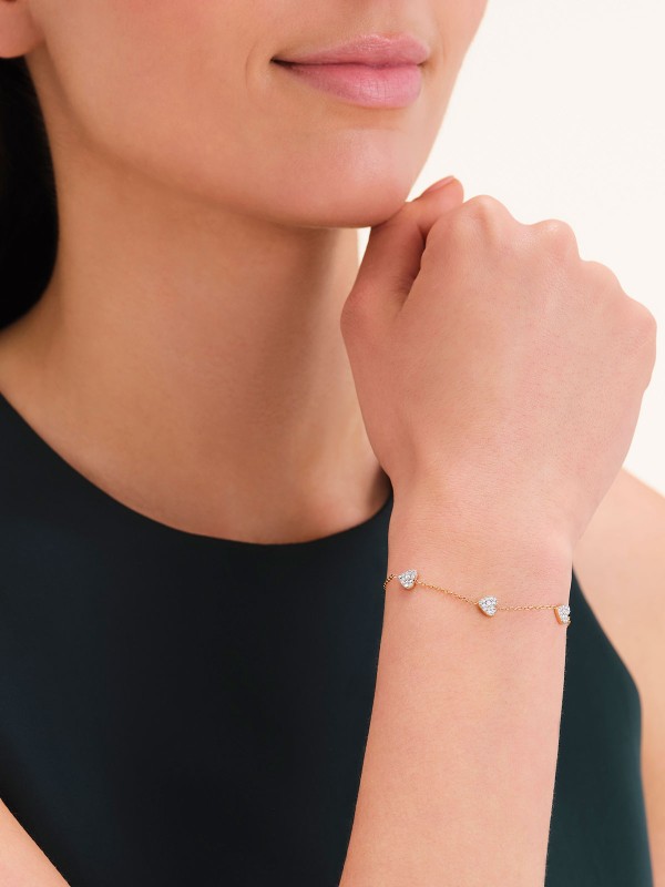 Nežna narukvica u zlatnom tonu sa tri viseća srca. Privesci ukrašeni cirkonima čine ovaj nakit od čelika elegantnim i razigranim.