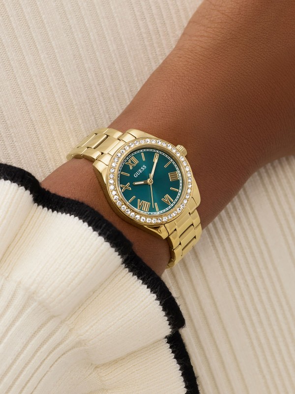 Elegantan GUESS Mini Luna ženski sat prečnika 30mm. Kućište i narukvica u zlatnom tonu sa cirkonima i plavozelenim brojčanikom. Vodootporan do 30m.